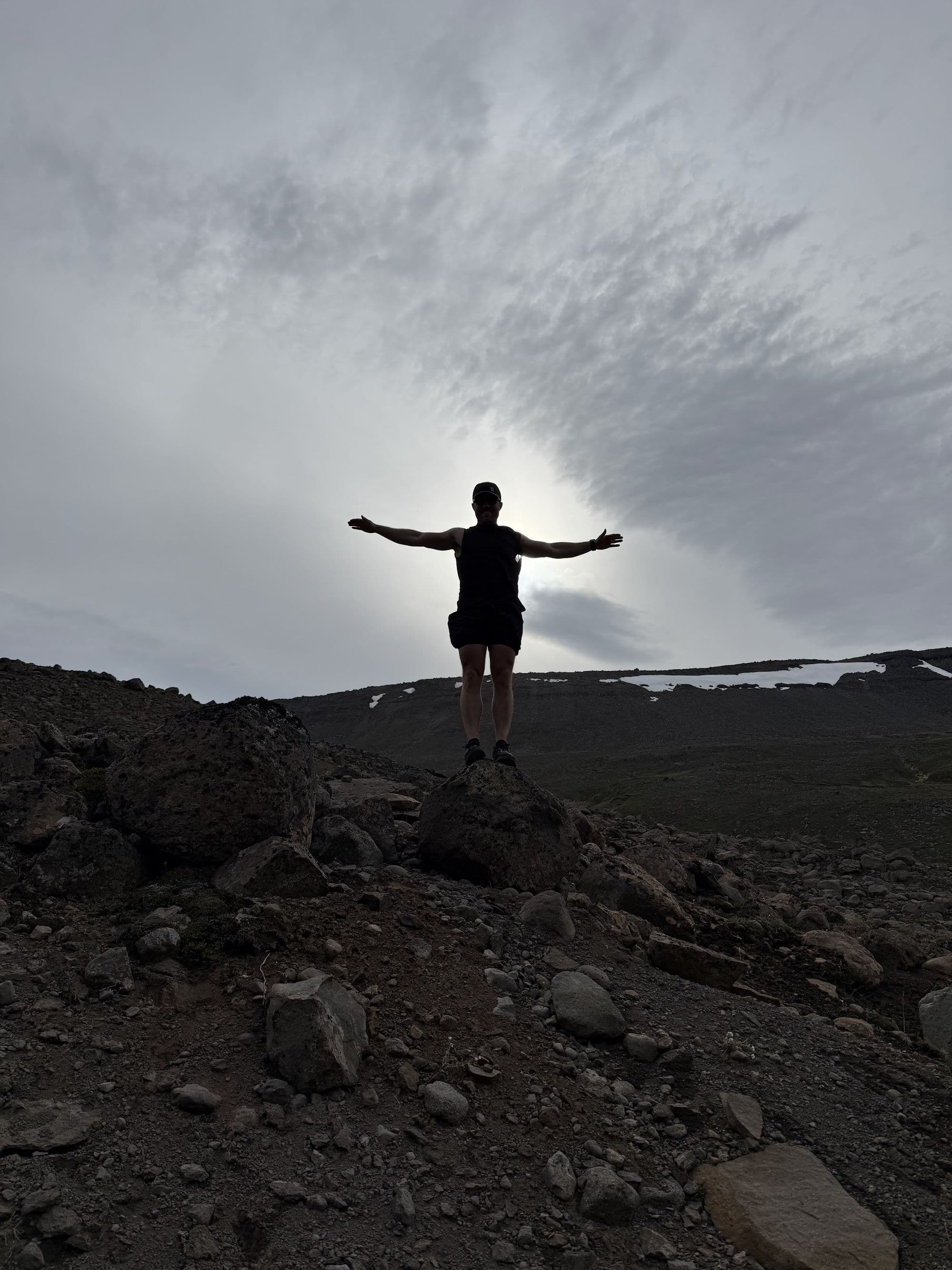 Justin True, arms wide on a volcanic ridge in Iceland