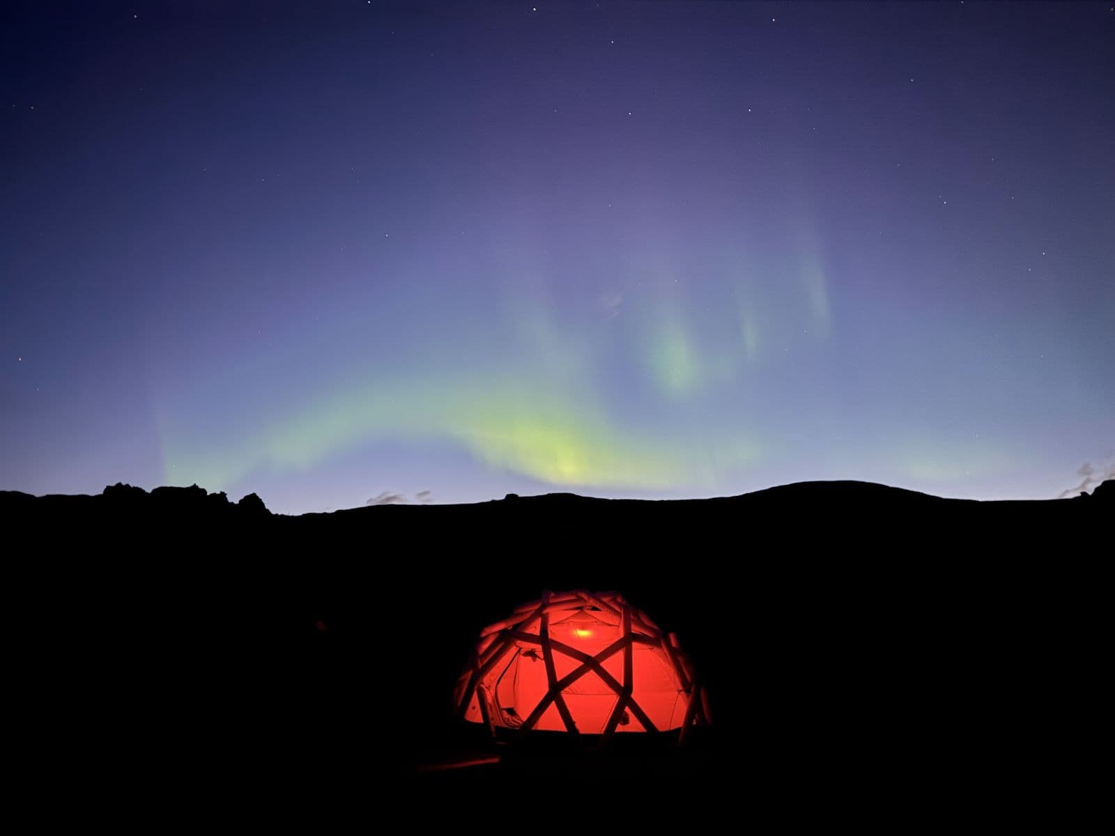 Northern lights over the glowing dome at camp, Iceland, August 2026