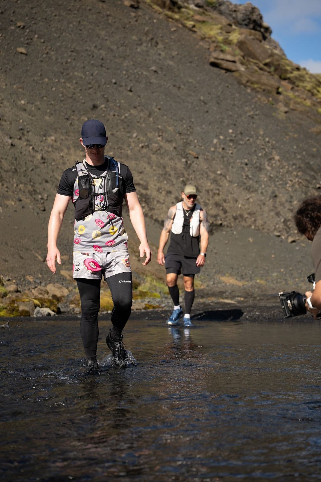 Two runners wading a cold river crossing