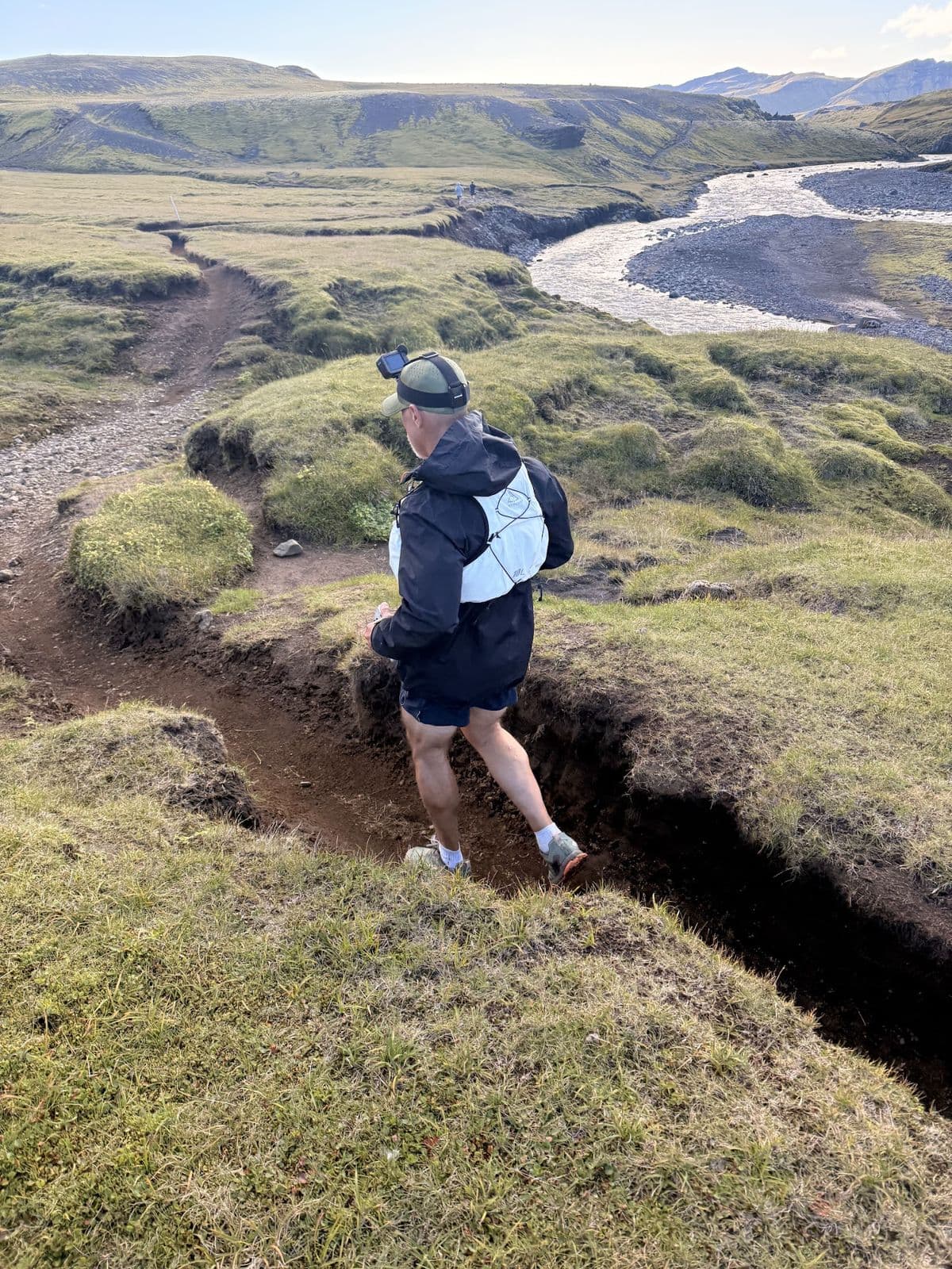 A runner on a rutted trail above braided glacial rivers