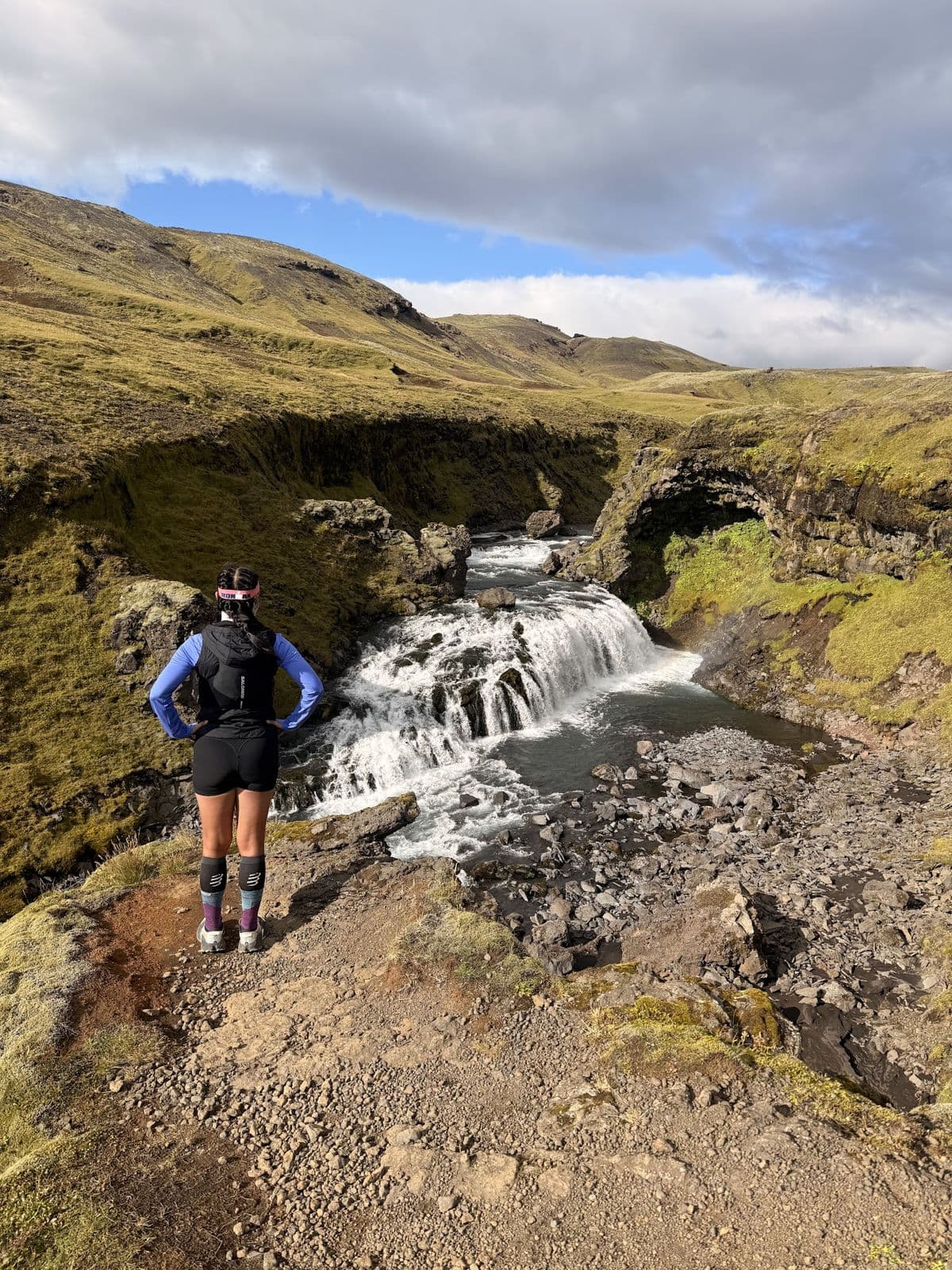 A runner on single track beside a canyon waterfall