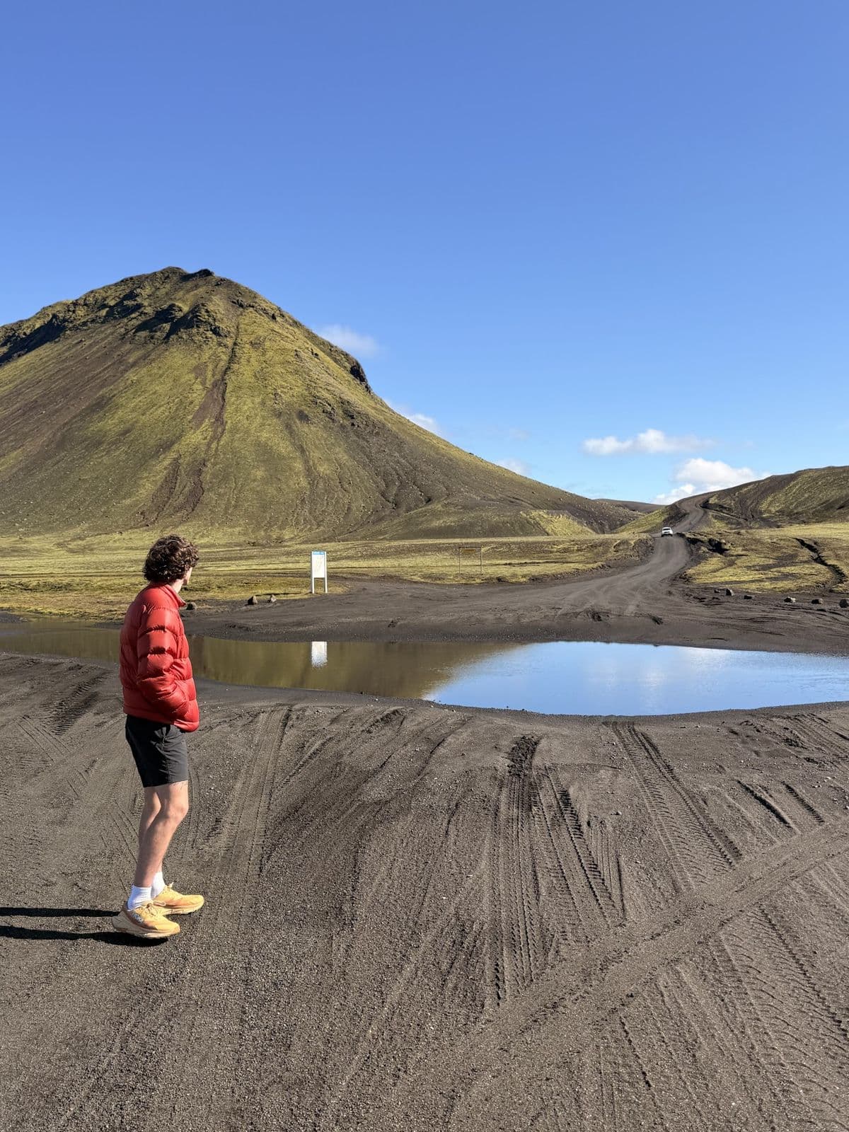 A runner dwarfed by a green volcanic cone